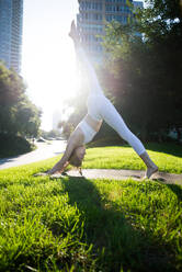 Beautiful sportive woman doing yoga meditation in a park - Girl relaxing with serene expression outdoors - DMDF03321
