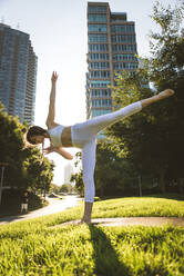Beautiful sportive woman doing yoga meditation in a park - Girl relaxing with serene expression outdoors - DMDF03325