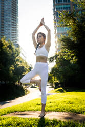 Schöne sportliche Frau macht Yoga-Meditation in einem Park - Mädchen entspannt mit heiterem Ausdruck im Freien - DMDF03338