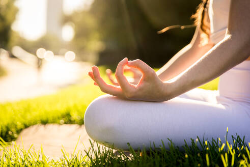 Beautiful sportive woman doing yoga meditation in a park - Girl relaxing with serene expression outdoors - DMDF03342