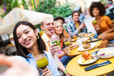 Multiracial young people together meeting and having party in a restaurant - Group of friends taking selfie while celebrating in a bar- Friendship and lifestyle concepts - DMDF03420