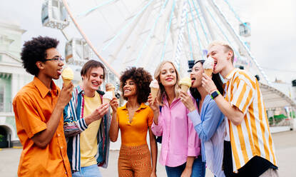 Gemischtrassige junge Leute, die sich in einem Freizeitpark treffen und Eis essen - Gruppe von Freunden mit gemischten Rassen, die Spaß im Freien haben - Freundschafts- und Lebensstilkonzepte - DMDF03440