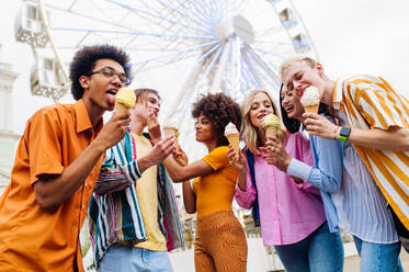 Gemischtrassige junge Leute, die sich in einem Freizeitpark treffen und Eis essen - Gruppe von Freunden mit gemischten Rassen, die Spaß im Freien haben - Freundschafts- und Lebensstilkonzepte - DMDF03441