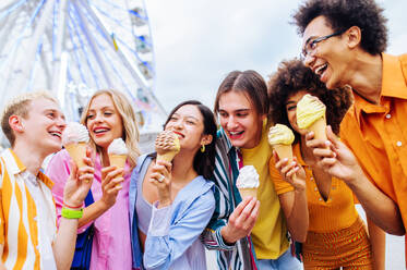 Gemischtrassige junge Leute, die sich in einem Freizeitpark treffen und Eis essen - Gruppe von Freunden mit gemischten Rassen, die Spaß im Freien haben - Freundschafts- und Lebensstilkonzepte - DMDF03451