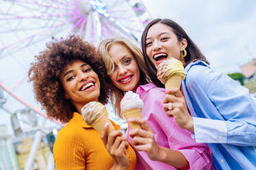 Gemischtrassige junge Leute, die sich in einem Freizeitpark treffen und Eis essen - Gruppe von Freunden mit gemischten Rassen, die Spaß im Freien haben - Freundschafts- und Lebensstilkonzepte - DMDF03458