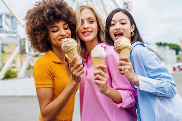 Multiracial young people together meeting at amusement park and eating ice creams - Group of friends with mixed races having fun outdoors - Friendship and lifestyle concepts - DMDF03459