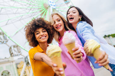 Gemischtrassige junge Leute, die sich in einem Freizeitpark treffen und Eis essen - Gruppe von Freunden mit gemischten Rassen, die Spaß im Freien haben - Freundschafts- und Lebensstilkonzepte - DMDF03460