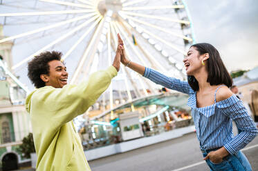 Multiracial young couple of lovers dating at theferry wheel in the amusement park - People with mixed races having fun outdoors in the city- Friendship, releationship and lifestyle concepts - DMDF03488