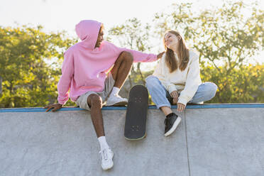Multicultural group of young friends bonding outdoors and having fun - Stylish cool teens gathering at urban skate park - DMDF03503