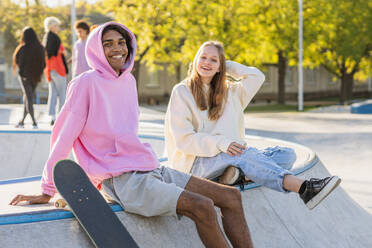 Multicultural group of young friends bonding outdoors and having fun - Stylish cool teens gathering at urban skate park - DMDF03505