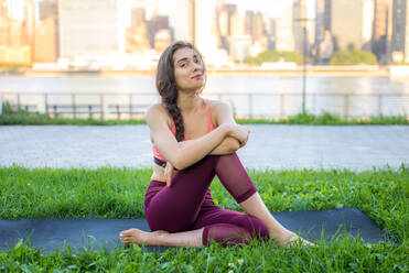 Beautiful sportive woman doing yoga meditation in a park - Girl relaxing with serene expression outdoors - DMDF03520