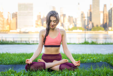 Beautiful sportive woman doing yoga meditation in a park - Girl relaxing with serene expression outdoors - DMDF03522