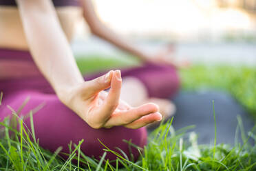 Beautiful sportive woman doing yoga meditation in a park - Girl relaxing  with serene expression outdoors stock