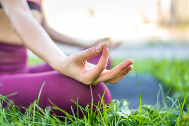 Beautiful sportive woman doing yoga meditation in a park - Girl relaxing with serene expression outdoors - DMDF03529
