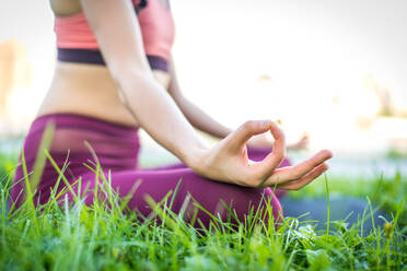 Beautiful sportive woman doing yoga meditation in a park - Girl relaxing with serene expression outdoors - DMDF03530