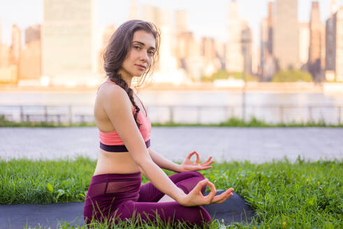 Schöne sportliche Frau macht Yoga-Meditation in einem Park - Mädchen entspannt mit heiterem Ausdruck im Freien - DMDF03532