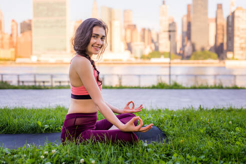 Schöne sportliche Frau macht Yoga-Meditation in einem Park - Mädchen entspannt mit heiterem Ausdruck im Freien - DMDF03533