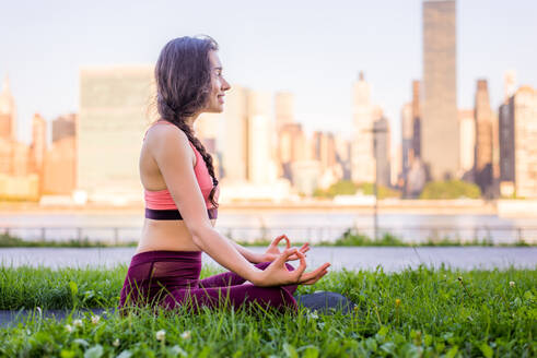Schöne sportliche Frau macht Yoga-Meditation in einem Park - Mädchen entspannt mit heiterem Ausdruck im Freien - DMDF03534
