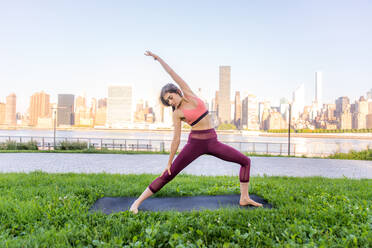 Schöne sportliche Frau macht Yoga-Meditation in einem Park - Mädchen entspannt mit heiterem Ausdruck im Freien - DMDF03535