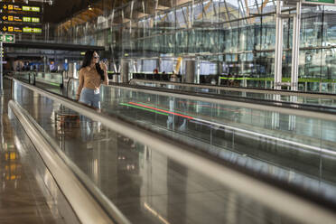 Junge Frau, die sich auf einem Fahrstuhl am Flughafen bewegt - JCCMF10723