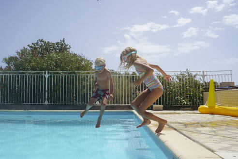 Fröhlicher Bruder und Schwester springen im Schwimmbad - NJAF00558