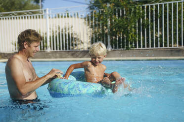 Vater spielt mit Sohn in aufblasbarem Schwimmring - NJAF00562