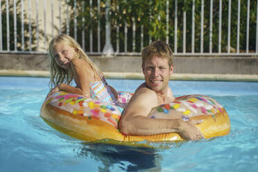 Lächelnd und Tochter spielen mit aufblasbarem Ring im Schwimmbad - NJAF00564