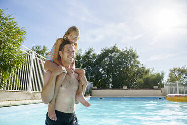 Smiling father carrying daughter on shoulders in swimming pool - NJAF00567