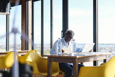 Ingenieur arbeitet am Tisch mit Tagebuch und Laptop in einem Restaurant - ASGF04440