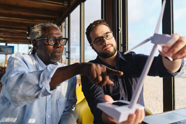 Engineers having discussion and examining wind turbine model in restaurant - ASGF04478