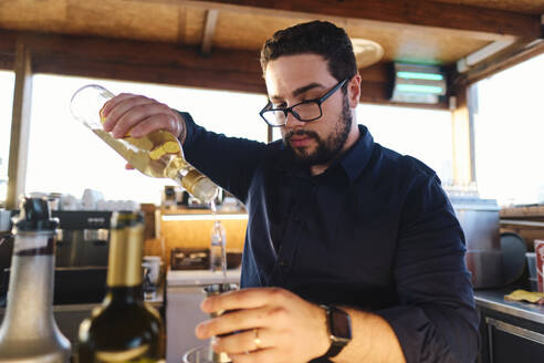 Junger Barkeeper bei der Zubereitung eines Getränks in einem Café - ASGF04487