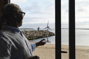 Zufriedener Ingenieur, der das Modell einer Windkraftanlage im Eingang eines Restaurants untersucht - ASGF04507