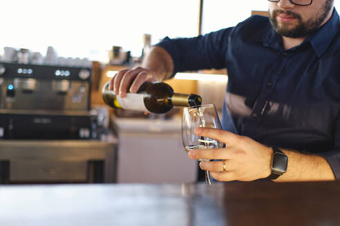 Barkeeper gießt Wein in ein Glas im Café - ASGF04521