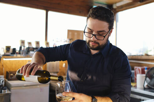 Junger Barkeeper gießt Wein in ein Glas in einem Café - ASGF04522