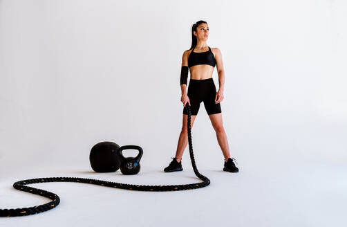 Junge Sportlerin, die in einem Fitnessstudio an Sportgeräten trainiert, fitte Frau, die trainiert, Konzept über Fitness, Wellness und Sportvorbereitung. - DMDF03551
