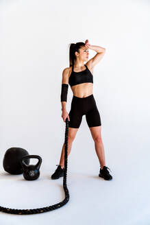 Junge Sportlerin, die in einem Fitnessstudio an Sportgeräten trainiert, fitte Frau, die trainiert, Konzept über Fitness, Wellness und Sportvorbereitung. - DMDF03553