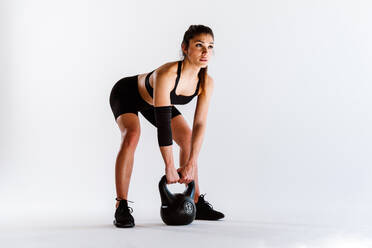 Junge Sportlerin, die in einem Fitnessstudio an Sportgeräten trainiert, fitte Frau, die trainiert, Konzept über Fitness, Wellness und Sportvorbereitung. - DMDF03562