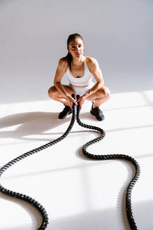 Junge Sportlerin, die in einem Fitnessstudio an Sportgeräten trainiert, fitte Frau, die trainiert, Konzept über Fitness, Wellness und Sportvorbereitung. - DMDF03585