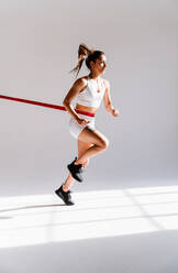 Junge Sportlerin, die in einem Fitnessstudio an Sportgeräten trainiert, fitte Frau, die trainiert, Konzept über Fitness, Wellness und Sportvorbereitung. - DMDF03587