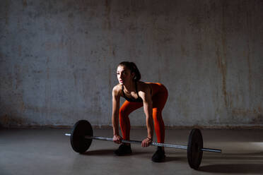 Junge Sportlerin, die in einem Fitnessstudio an Sportgeräten trainiert, fitte Frau, die trainiert, Konzept über Fitness, Wellness und Sportvorbereitung. - DMDF03598
