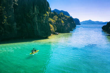 Pärchen beim Kajakfahren an einem tropischen Strand mit blauem Wasser und Palmen - El Nido, Palawan, Philippinen - DMDF03611