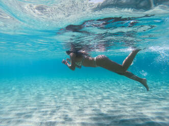 Frau schwimmt unter Wasser an einem tropischen Strand mit blauem Wasser und Palmen - El Nido, Palawan, Philippinen - DMDF03614