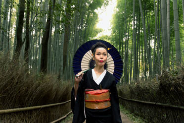 Asiatische Frau im traditionellen japanischen Kimono im Bambuswald in Kyoto, Japan - DMDF03637