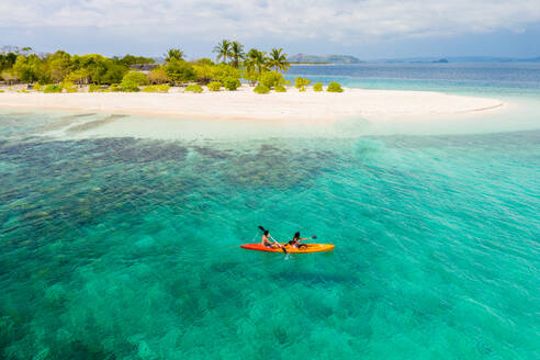 Pärchen beim Kajakfahren an einem tropischen Strand mit blauem Wasser und Palmen - Coron, Philippinen - DMDF03650