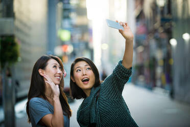 Two girlfriends meeting outdoors and having fun - Japanese people bonding on Tokyo streets - DMDF03665