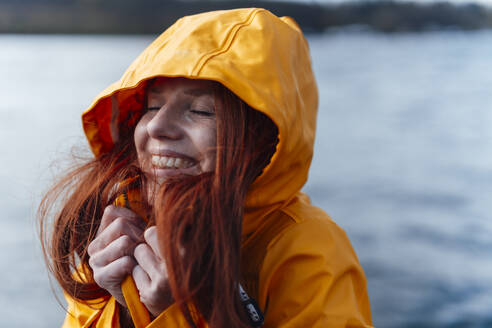 Smiling redhead woman wearing yellow jacket - KNSF09747