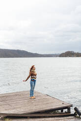 Unbekümmerte Frau steht auf einem Pier am See - KNSF09757