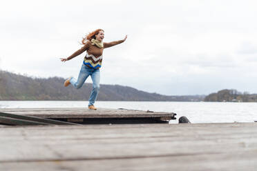 Woman standing on one leg under sky by lake - KNSF09761