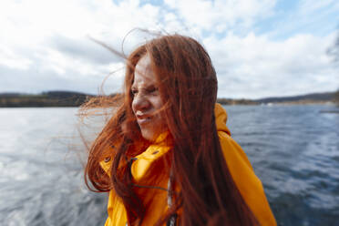 Rothaarige Frau mit Gesichtsausdruck vor einem See - KNSF09770