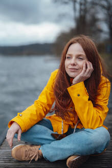 Thoughtful woman sitting cross-legged on pier - KNSF09777